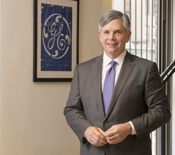 Larry Culp standing by a GE logo picture.