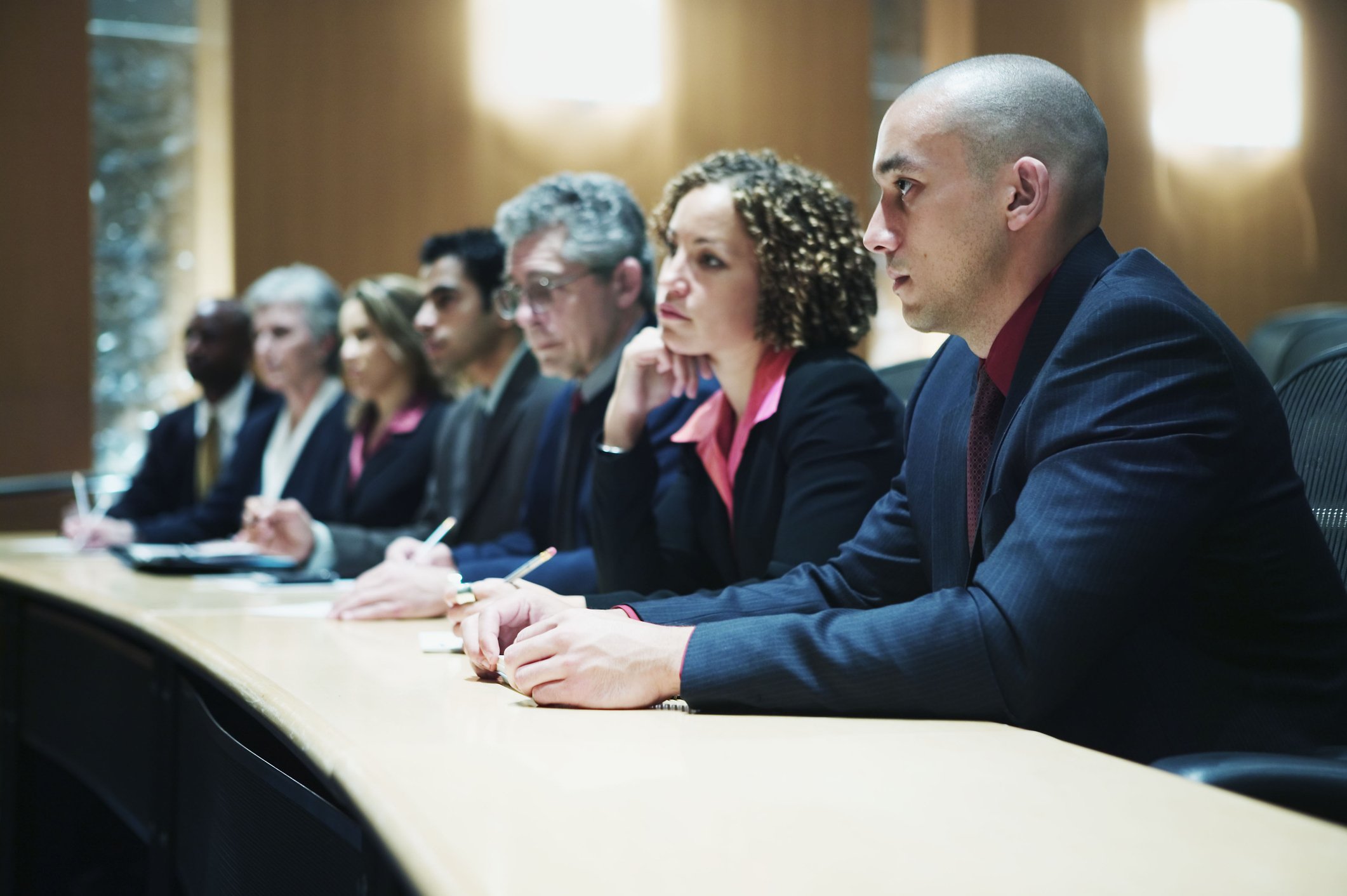 A group of shareholders consider a presentation while sitting at a long table.