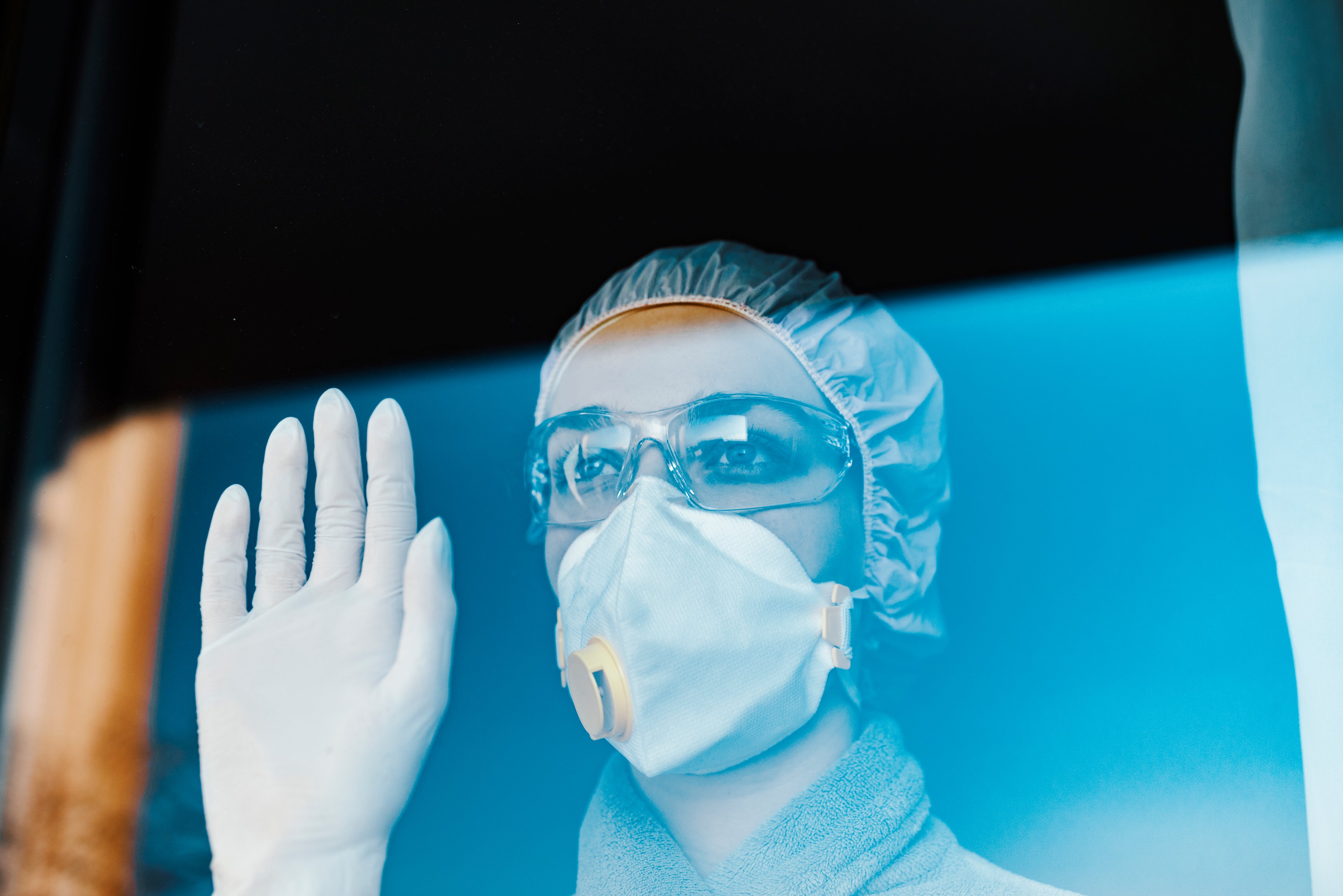 Healthcare worker in personal protective equipment, looking out through a window
