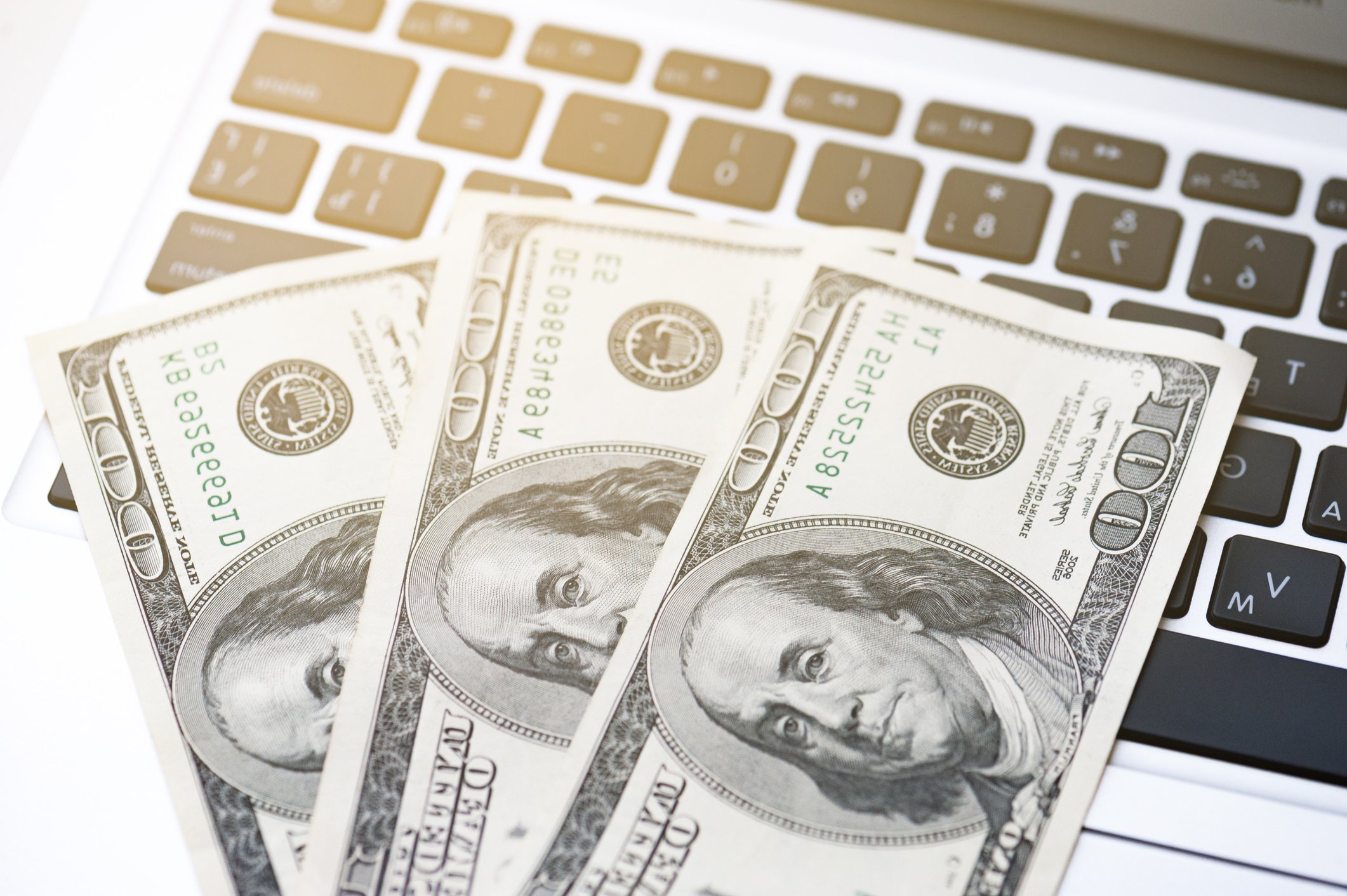 Three $100 bills on top of a computer keyboard