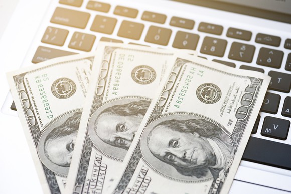 Three $100 bills on top of a computer keyboard