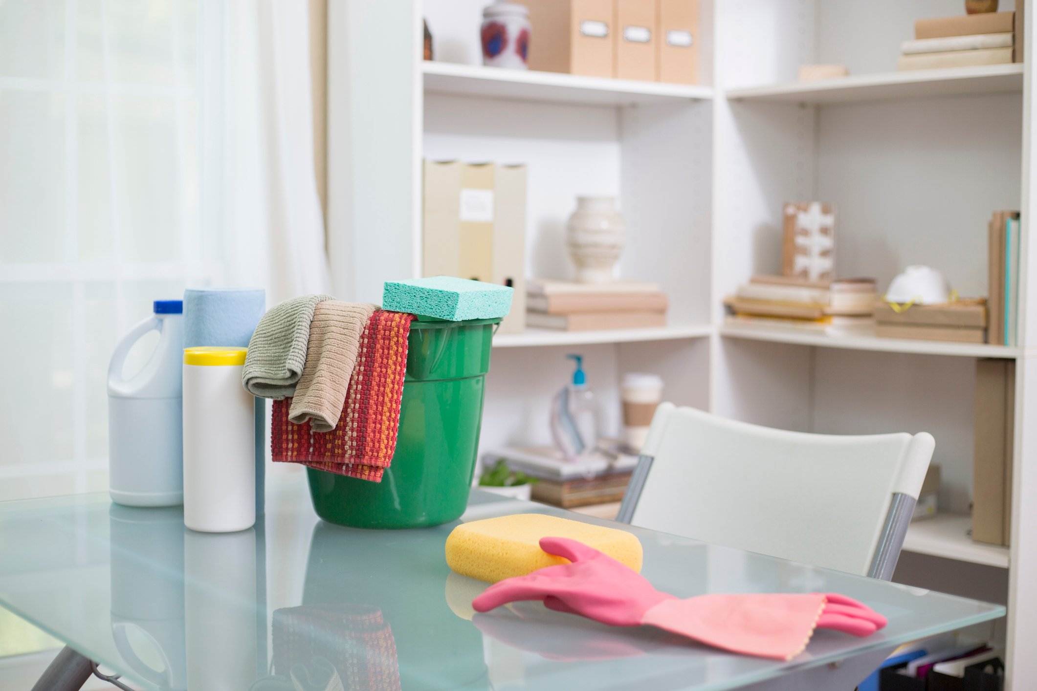 Bottles of bleach and cleaning equipment sitting on a table.