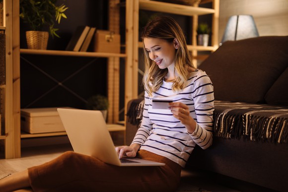 Woman shopping online, holding a card.