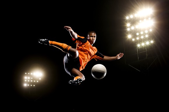 Soccer player jumping to kick ball.