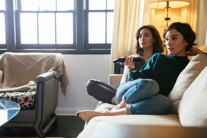 Two people on couch watching TV