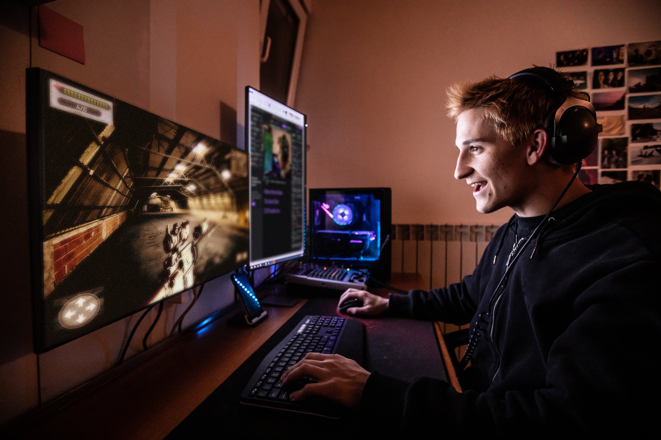 A young man sitting in front of multiple monitors while playing a video game on a PC.