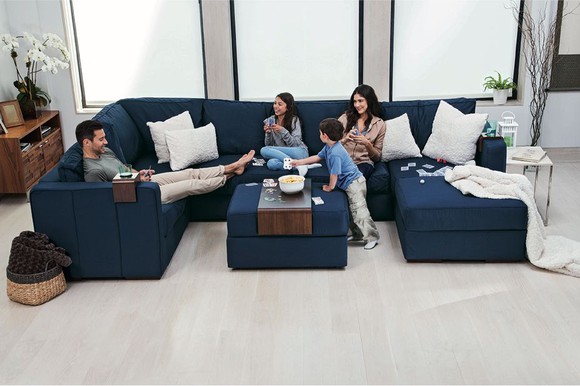 Family of four spread out on a giant blue couch from Lovesac.