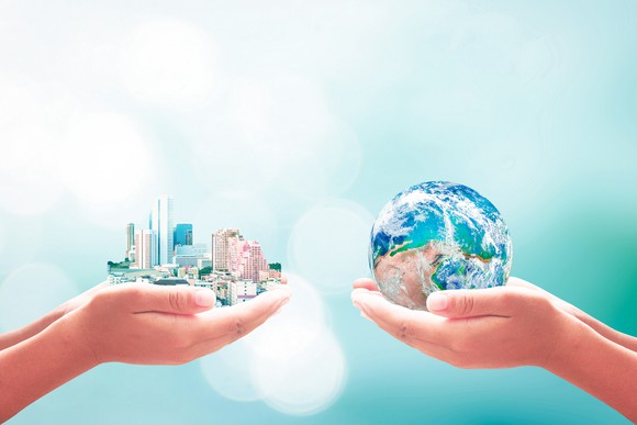 Two children's hands, one holding a cityscape and the other holding a globe