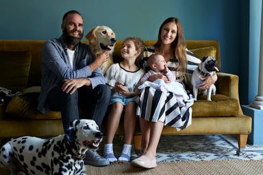 a family sitting on a couch with three dogs
