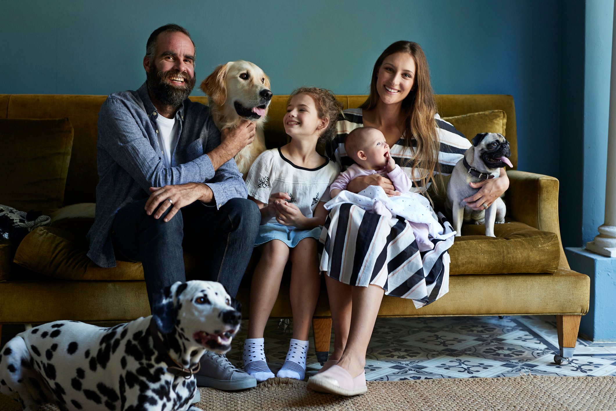 a family sitting on a couch with three dogs