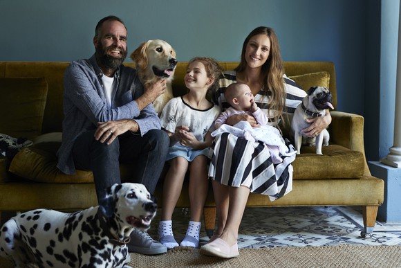 a family sitting on a couch with three dogs