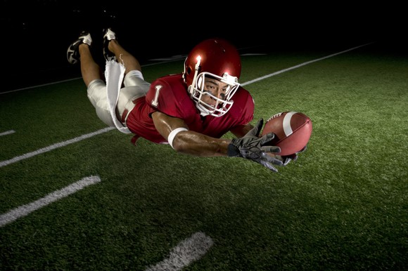 Football player making a diving catch.