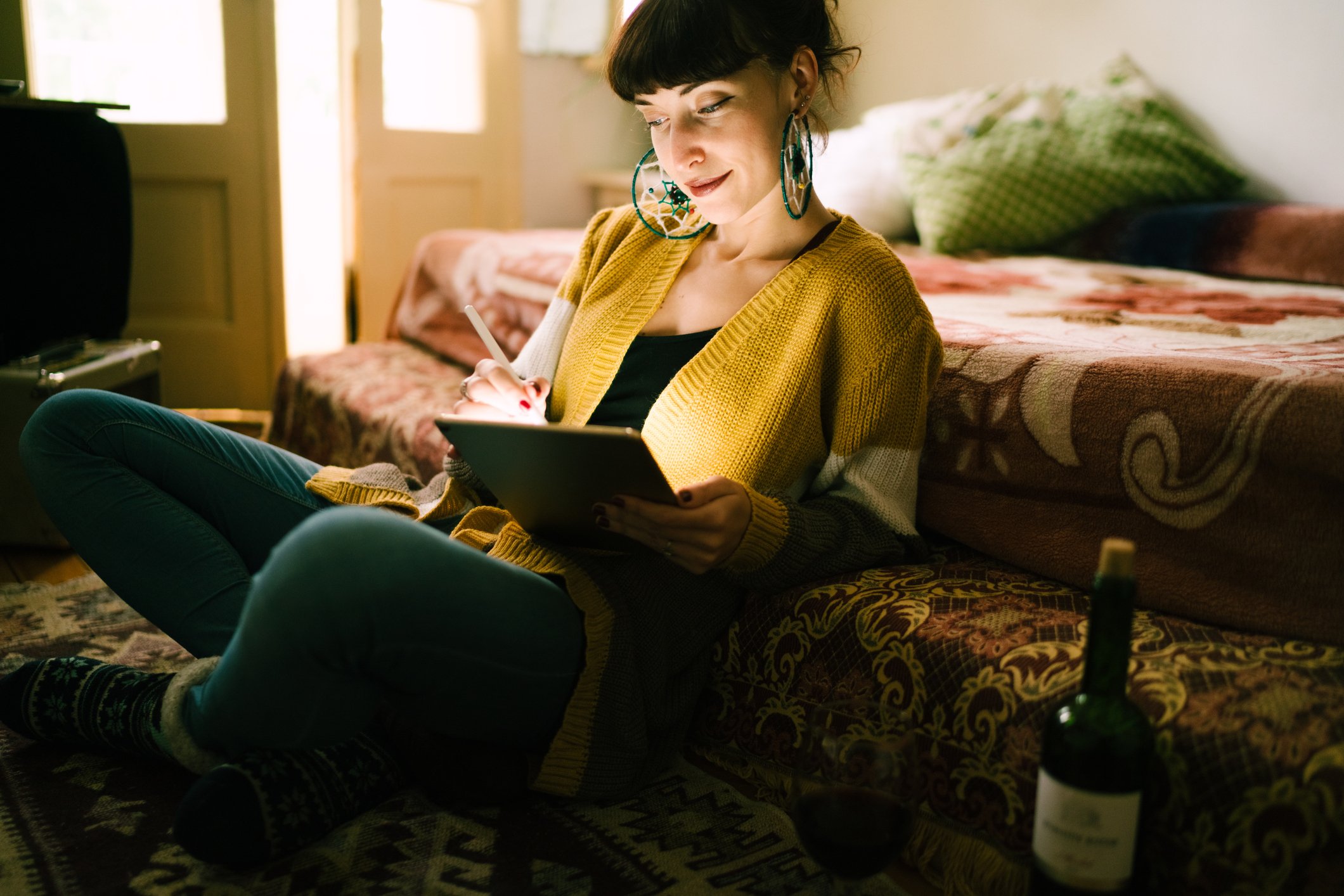 A young woman works on her tablet at home.