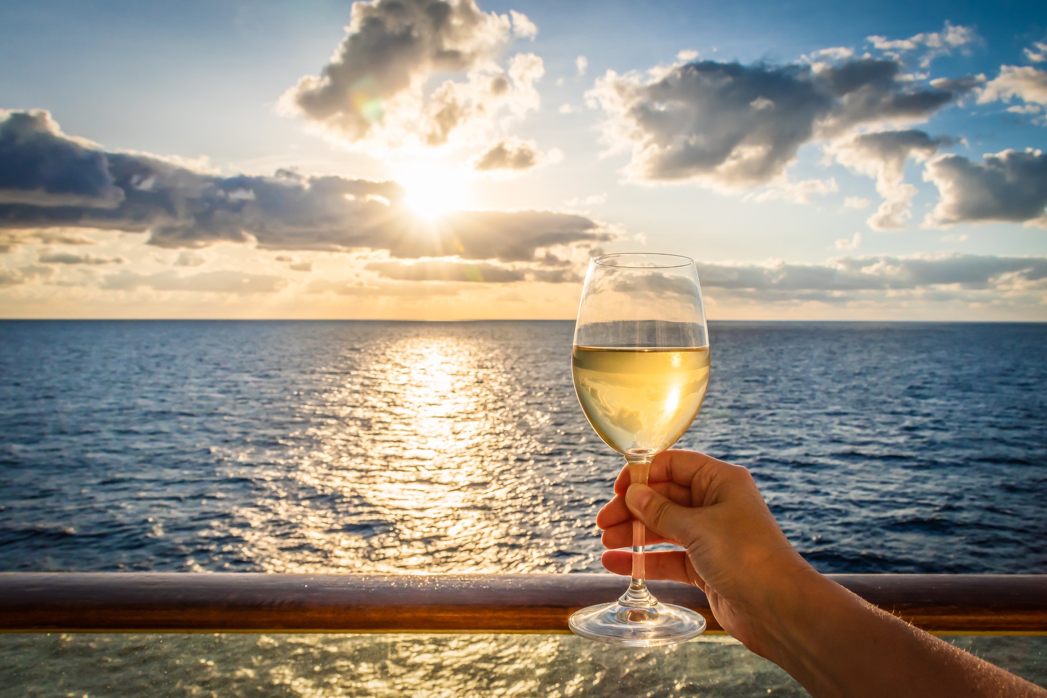A person is holding a wine glass up to the sky while onboard a cruise ship.
