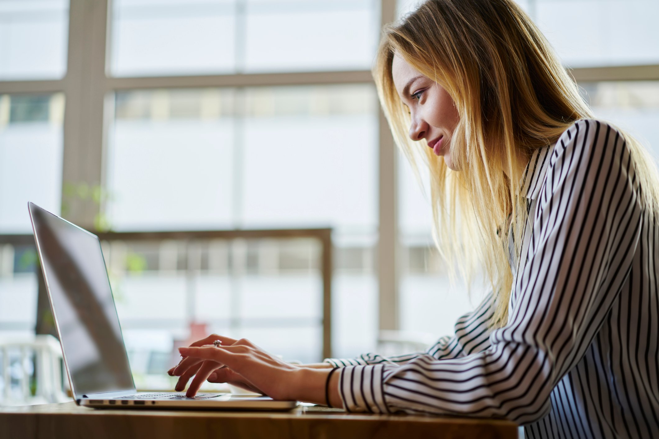 An investor sits at her laptop and studies stocks to buy.
