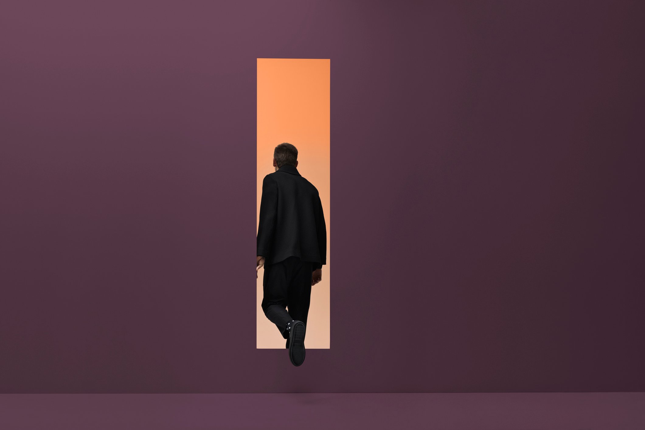 Man walking threw rectangular opening in colored room