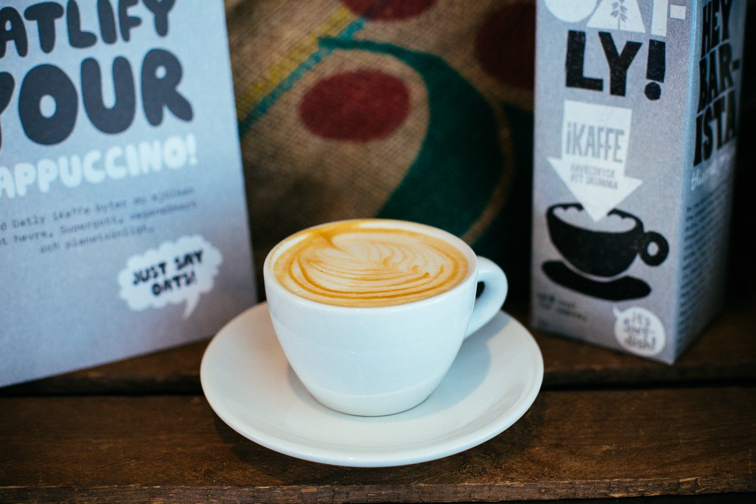 Oatly products surrounding a cup of designer coffee.