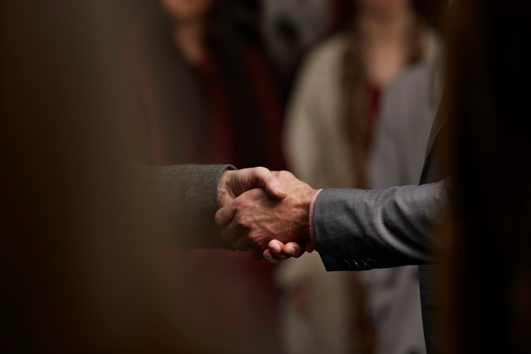Close up of two men dressed in business suits shaking hands.