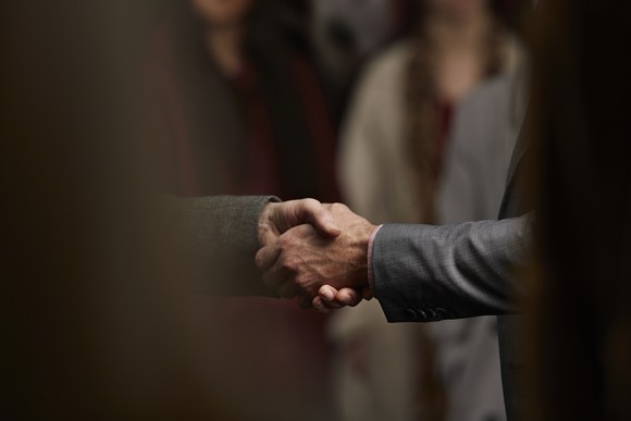Close up of two men dressed in business suits shaking hands.