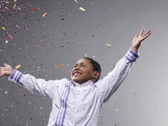 A child celebrates as confetti rains down.