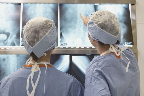 Two doctors consult several X-ray scans of the lumbar region.