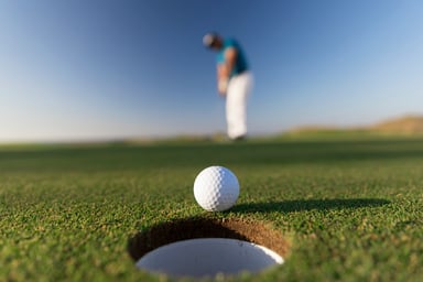 Person Putting Golf Ball into Hole
