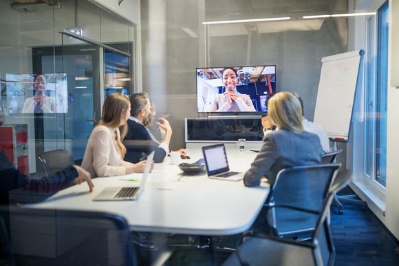 People meeting in boardroom with virtual participant on screen