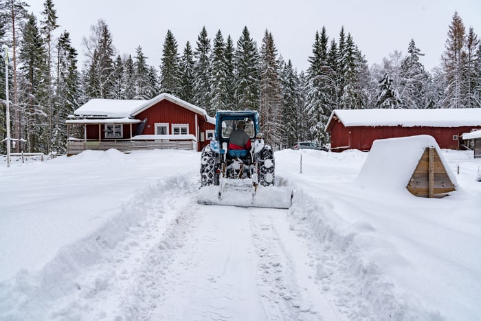 A tractor working on a home farm after a snowfall.