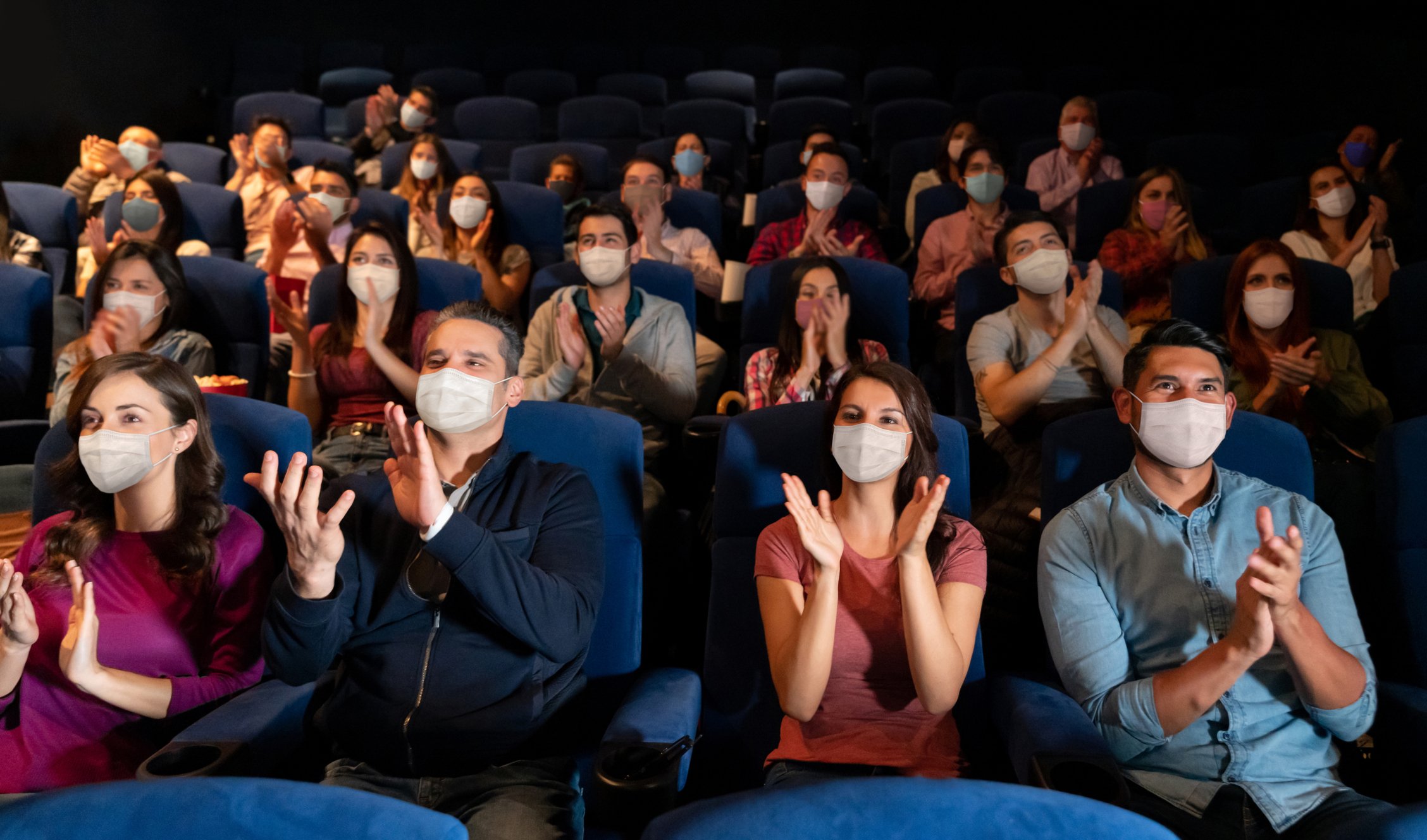 masked movie theater audience cheering