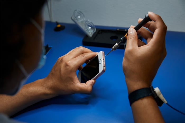 A technician using a tool on an Apple iPhone.