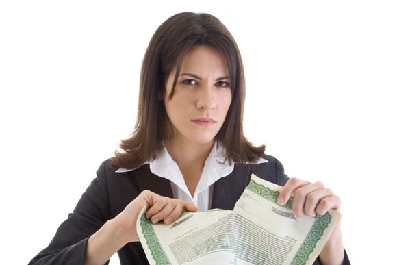 A woman rips a stock certificate in half.