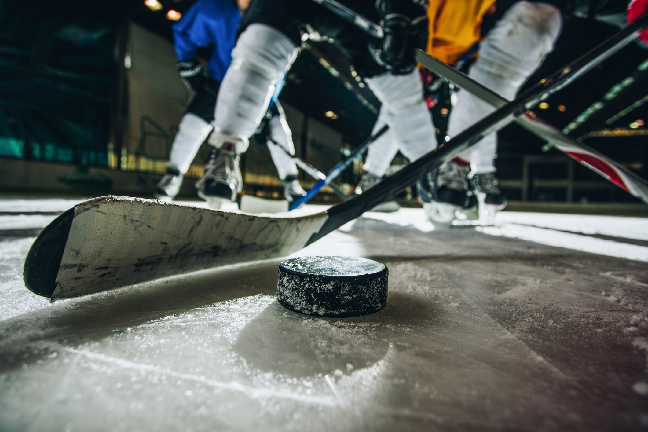 Ice-level view of the puck and players in a hockey game.