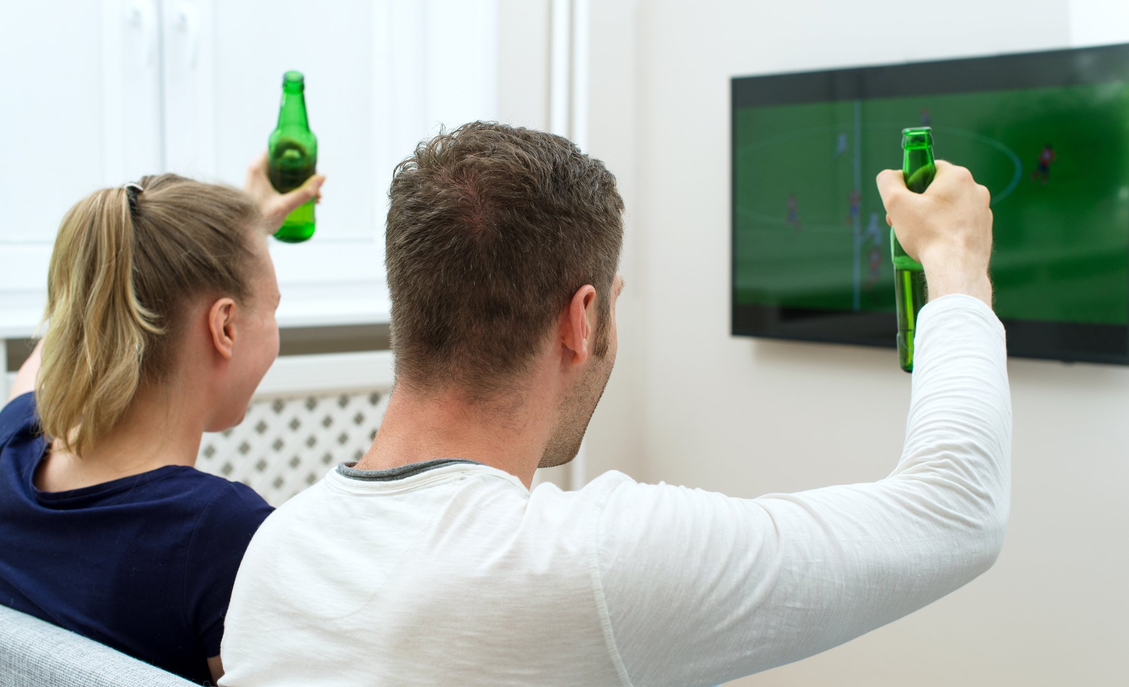 An enthusiastic couple watching a football sportscast.