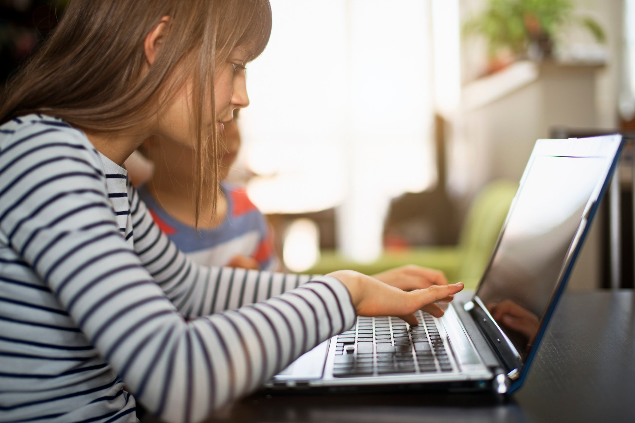 A young girl uses a laptop.