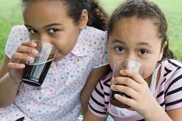 Two little girls drinking cola.