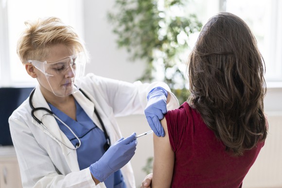 A doctor in her office vaccinates a patient with a coronavirus vaccine.