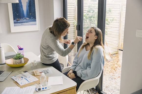 Two women using an at-home coronavirus test kit. 