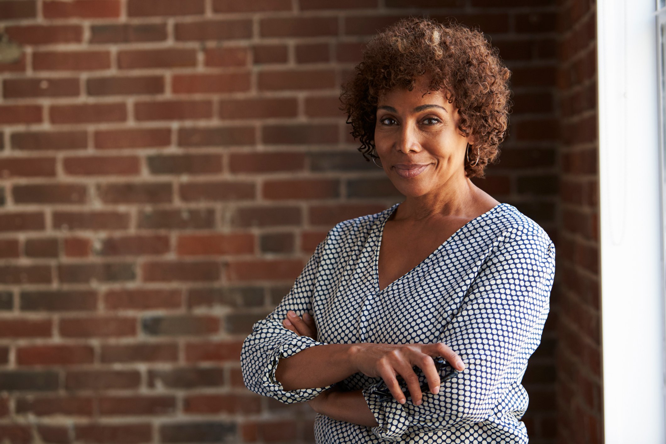 Woman with arms folded and smiling at the camera. 