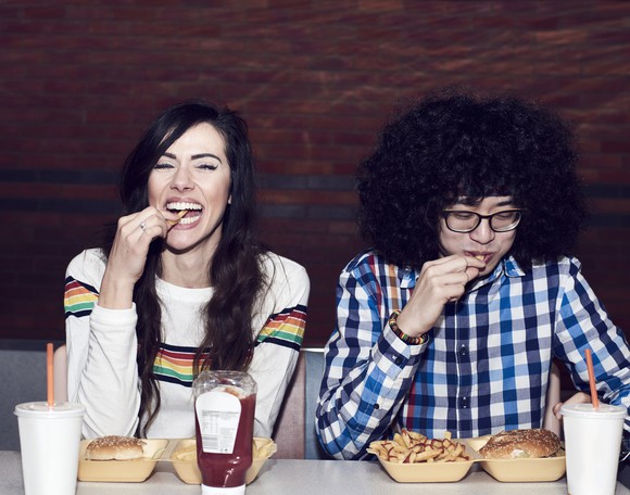 two people eating burgers and fries.