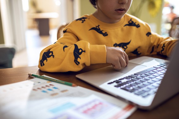 A child attends an online class on a laptop.