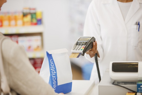 A pharmacist completing a payment card purchase at a pharmacy.