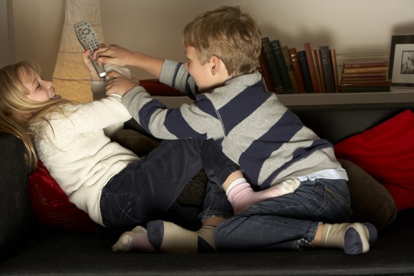 Two kids fighting over a TV remote.