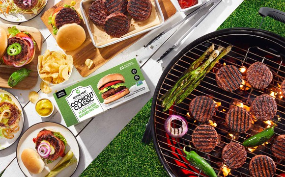 Hamburgers made with Beyond Burger from Beyond Meat are displayed cooking on a grill and complete on a table.