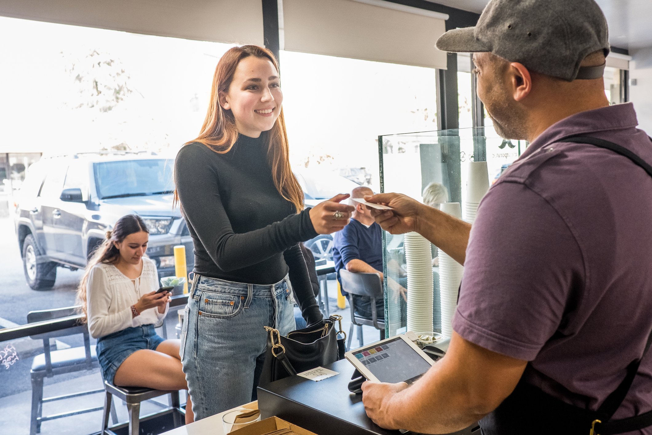 A person pays at a digital point of sale device in a store.