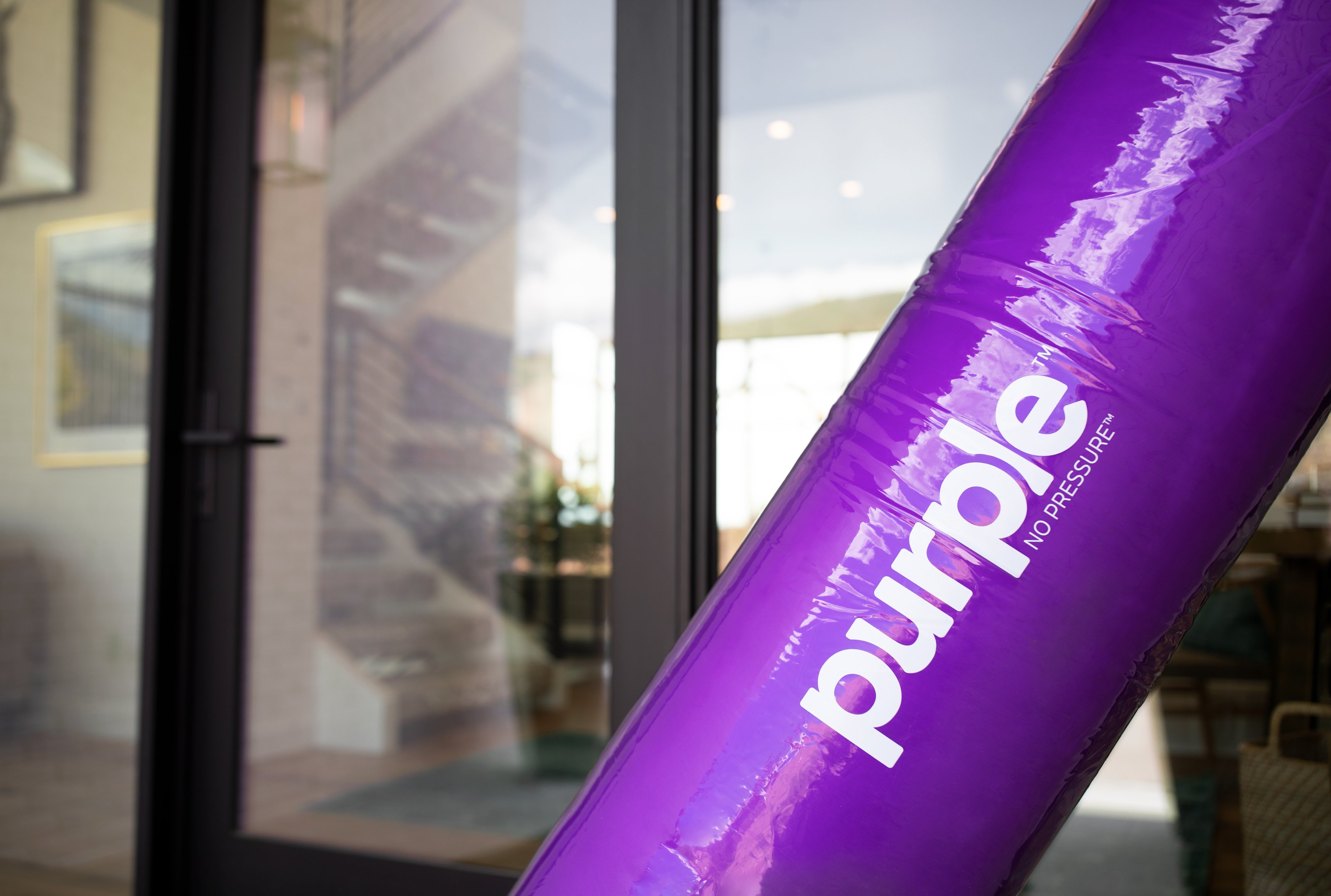 A rolled-up mattress from Purple Innovation sits outside someone's house.