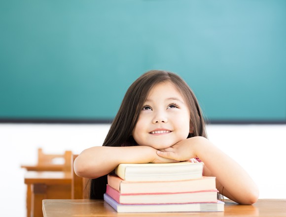 Girl leaning on pile of books and thinking