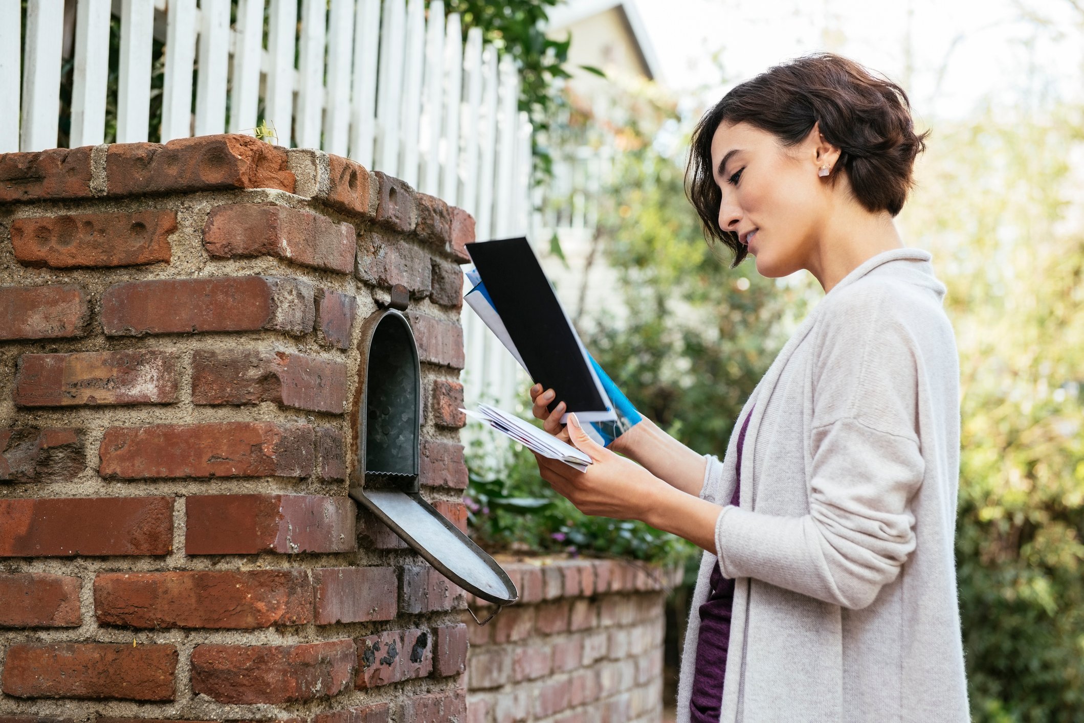 A woman getting her mail from a mailbox.