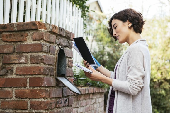 A woman getting her mail from a mailbox.