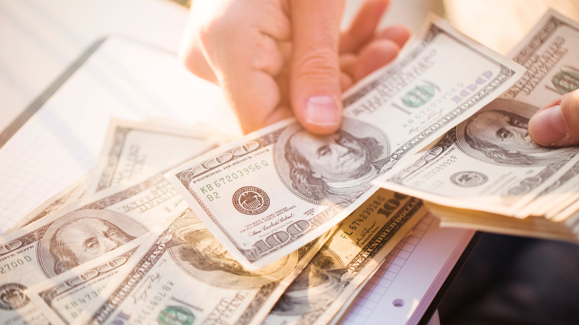 An investor counts out $100 dollar bills on his desk.