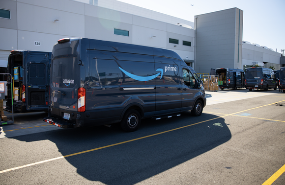 Amazon Prime delivery vans parked outside a large warehouse facility.